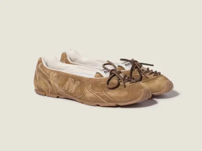 Pair of tan New Balance sneakers with brown laces on a pale background