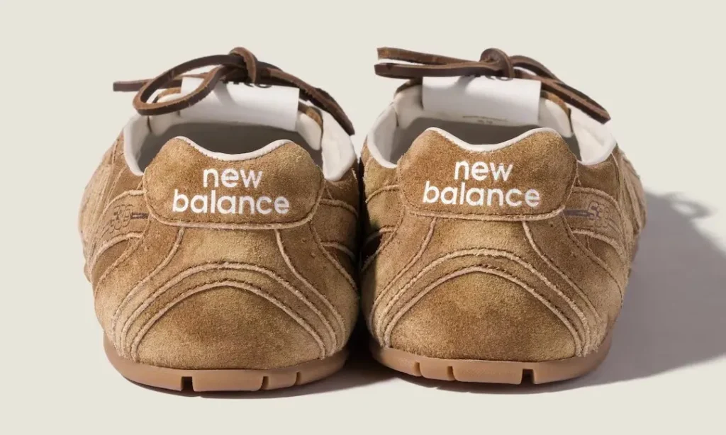Pair of tan suede New Balance sneakers facing forward, with brown laces and gum soles on a pale surface