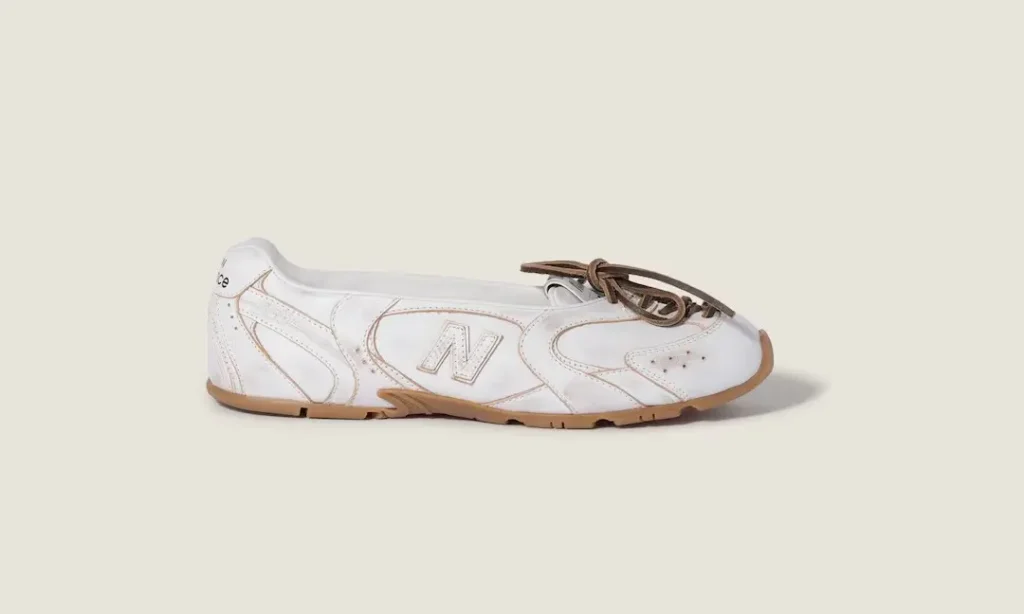White New Balance sneaker with brown laces and gum sole, shown in profile against a beige background