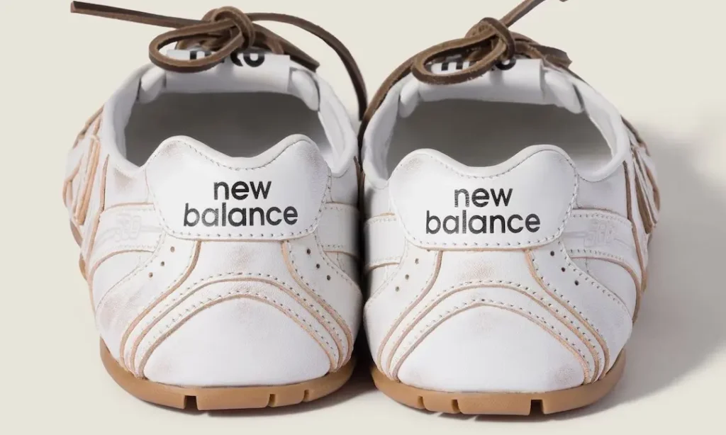 Pair of white New Balance shoe with gum soles and brown laces, shown front-facing against a pale background