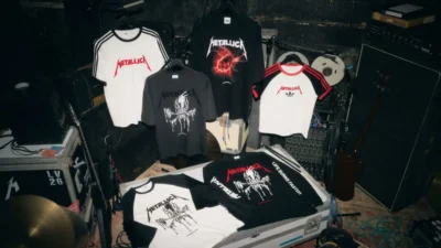 Metallica Tee hang and lie on a road case among drums, audio equipment, cables, and musical gear backstage