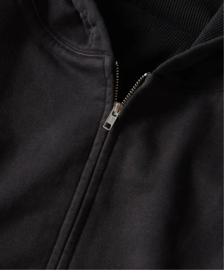 Close-up of a black double-face hoodie showing its silver front zipper and textured knit hood lining