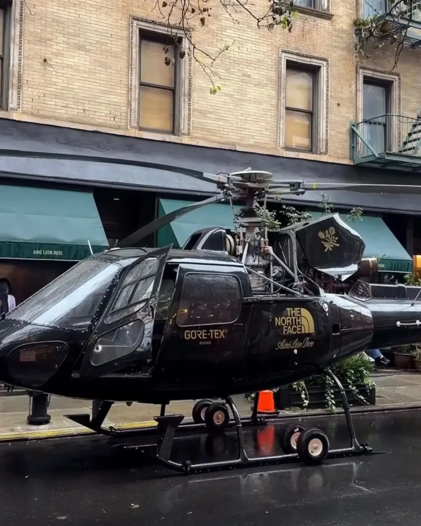 Black helicopter parked on a wet city street, marked with GORE-TEX and The North Face logos