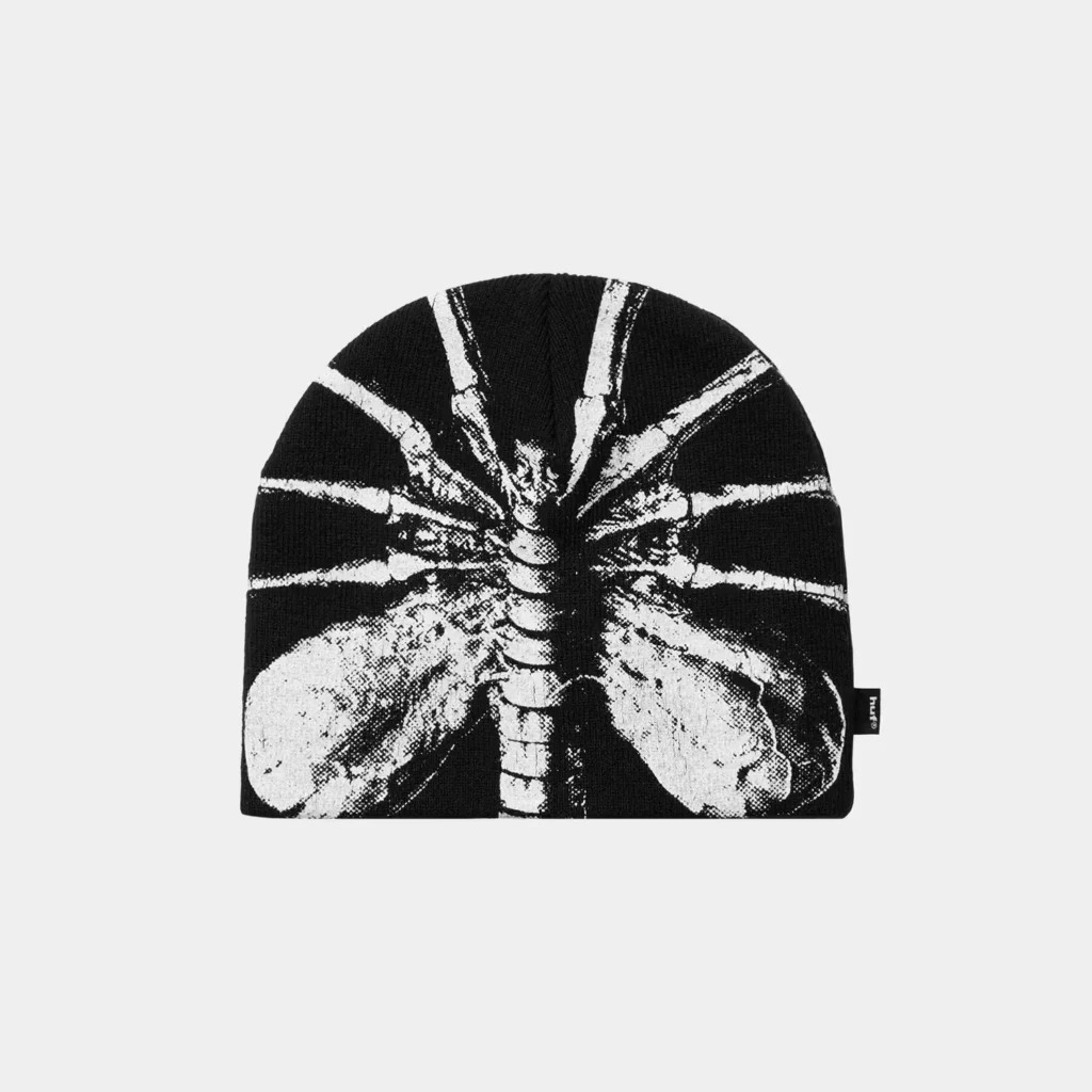 Black knit beanie featuring a high-contrast white Xenomorph graphic with radiating lines, shown against a light gray