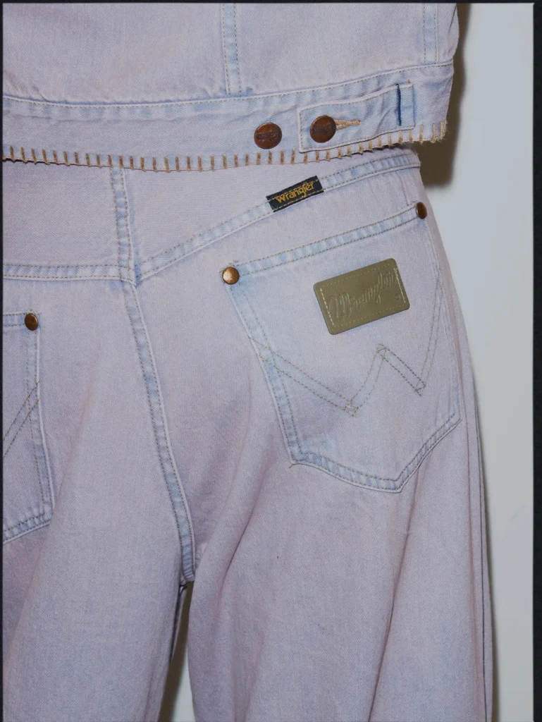 Close-up of pale lavender Wrangler jeans with stitched back pockets, copper rivets, waistband buttons and logo patch