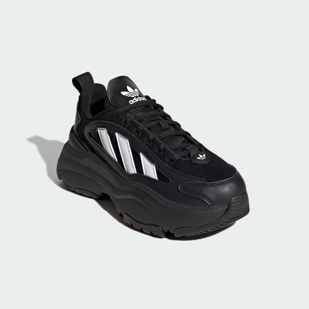 Black Adidas shoe with white three-stripe panels, chunky sole, and logo, isolated on a light gray background