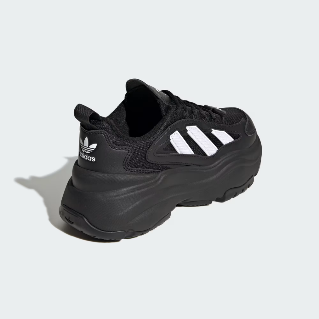 Black Adidas shoe with white three stripes and chunky sole on a light gray background