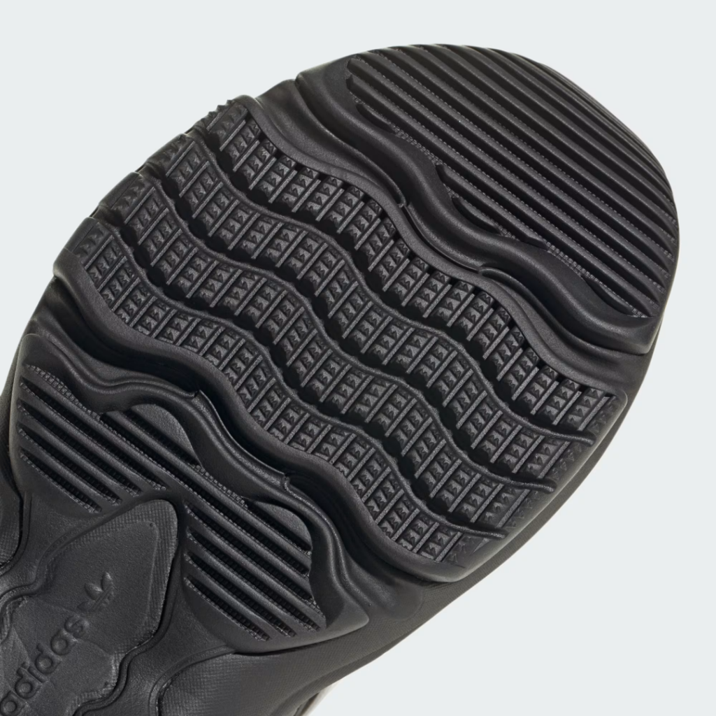Close-up of a black Adidas shoe sole with wavy grooves, ribbed sections, and textured triangular tread blocks