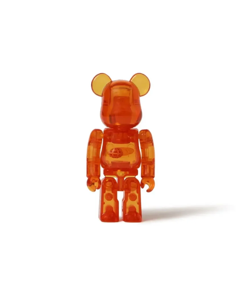 Translucent orange bear-shaped toy standing against a white background, casting a shadow to the right