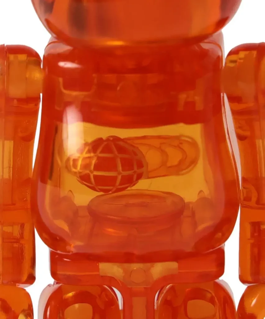 Close-up of a translucent orange toy robot with a globe emblem visible through its torso against a white background