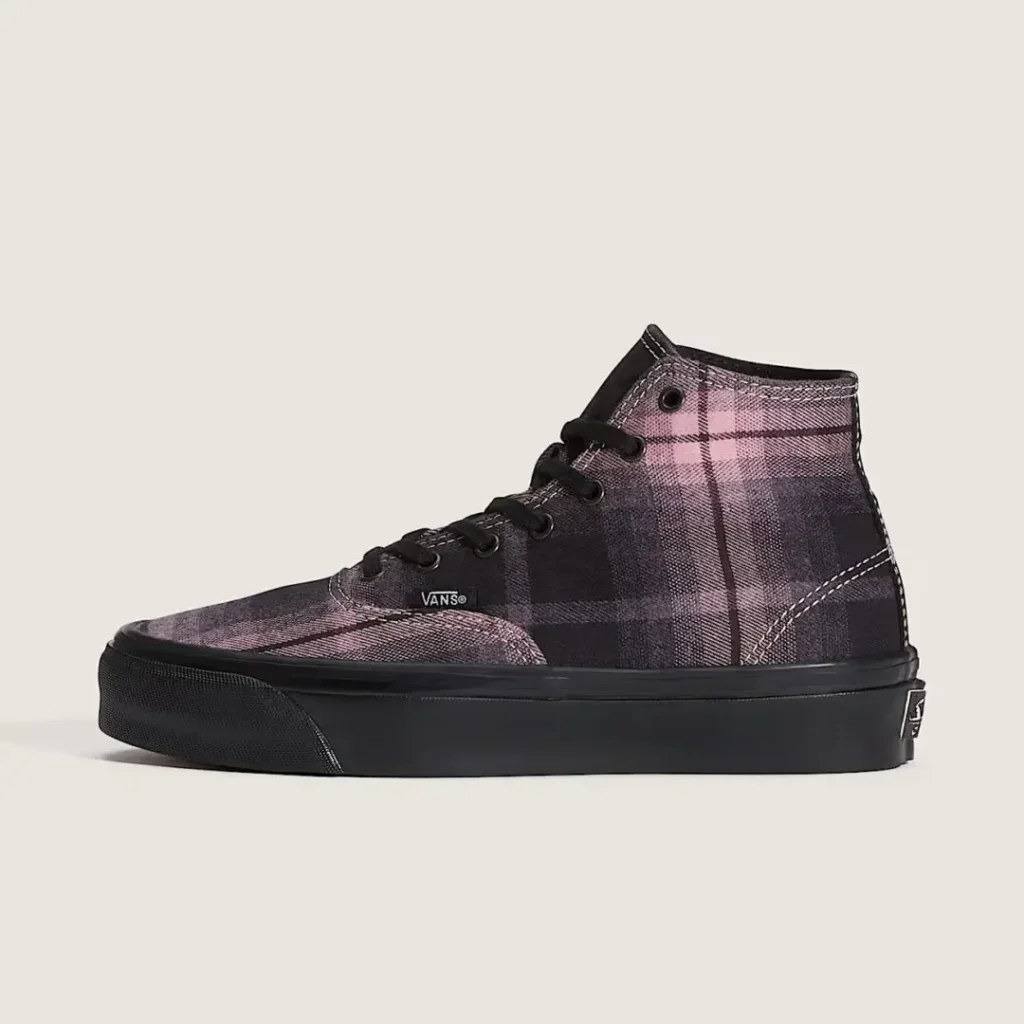 High-top Vans sneaker in a pink and black plaid pattern with black laces and a thick black rubber sole on a plain background