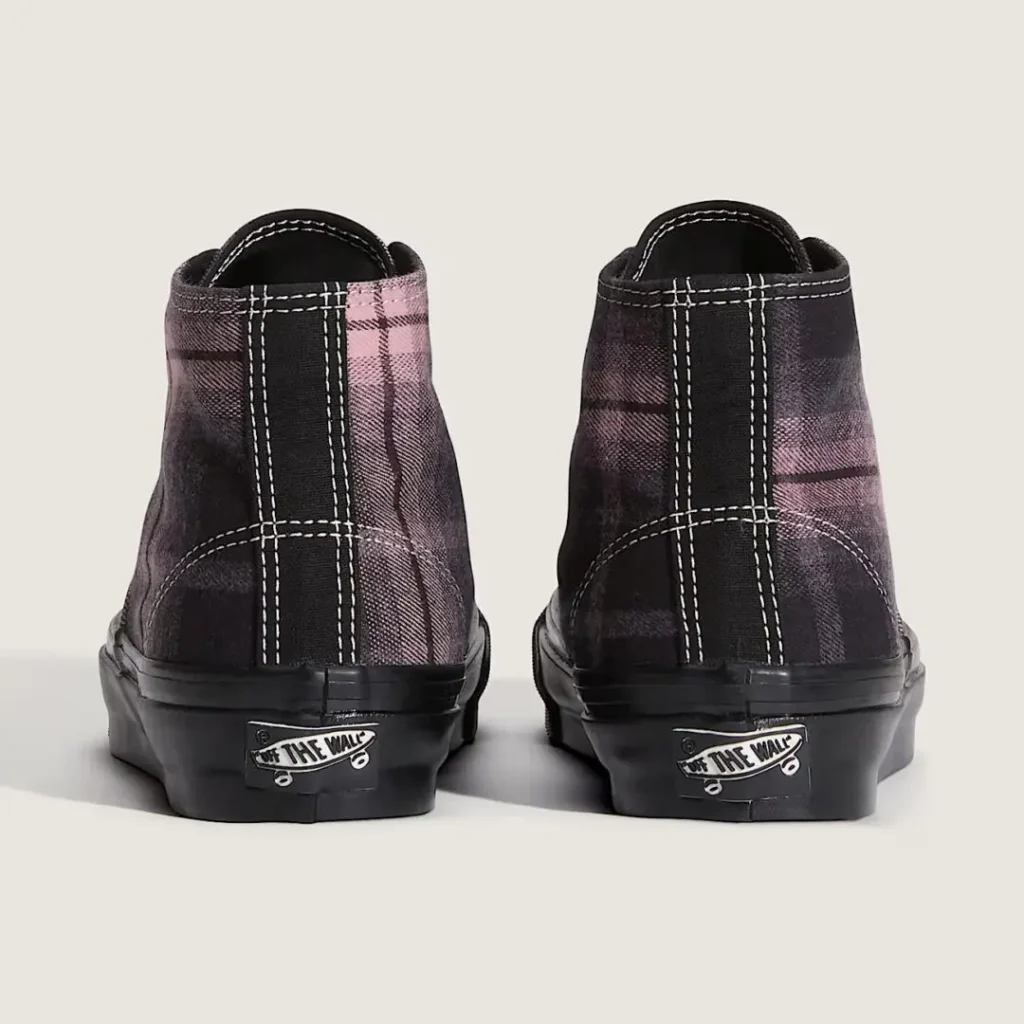Pair of black-and-pink plaid high-top shoe viewed from the back, with white stitching and “Off the Wall” heel logos