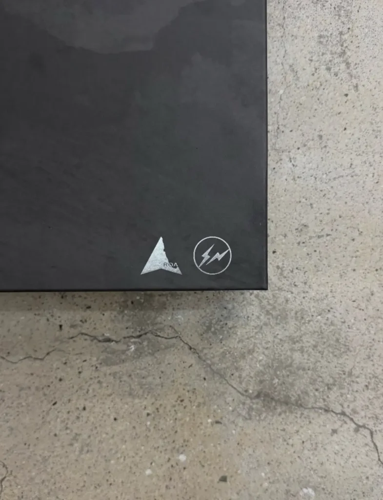 Black box corner with silver triangular and circular lightning logos on a cracked concrete floor