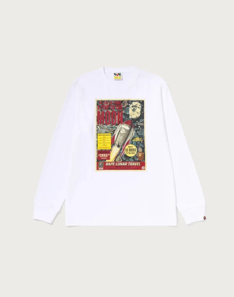 White long-sleeve T-shirt with a vintage-style lunar travel graphic, rocket, moon, and red lettering, laid flat on a pale