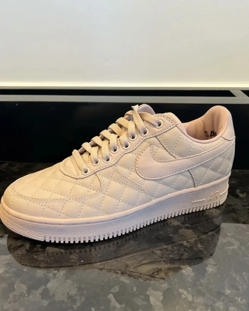 White quilted low-top sneaker with laces and swoosh logo on a dark stone surface