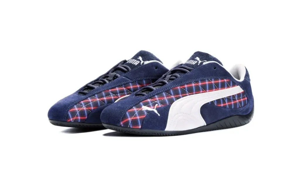 Pair of navy Puma sneakers with red-and-blue plaid panels, white side stripes, and black soles on a white background