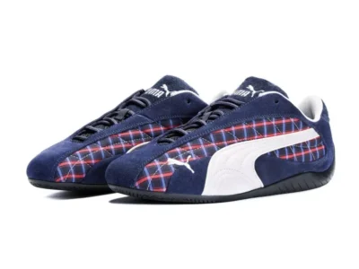 Pair of navy Puma sneakers with red-and-blue plaid panels, white side stripes, and black soles on a white background