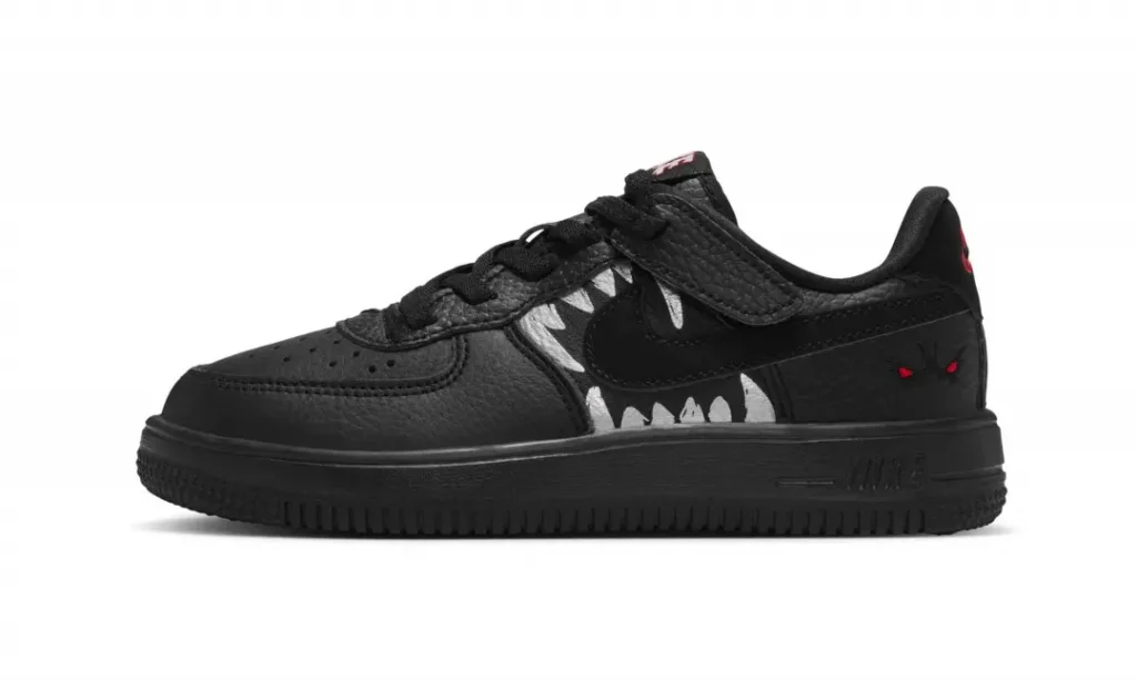 Black low-top shoe with texture panel, white jag detail, red accents, and a thick black sole on a white background