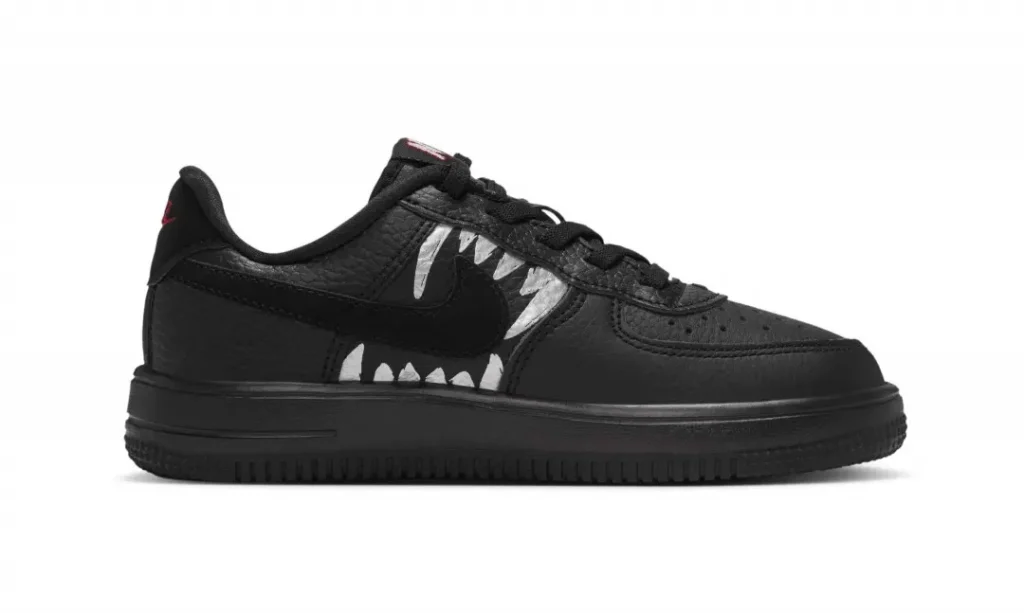 Black low-top shoe with a black swoosh and silver jag accents, shown in profile against a white background