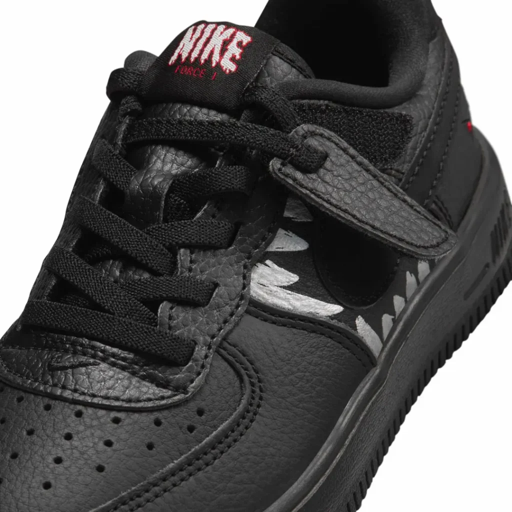 Close-up of a black Nike Air Force 1 shoe with textured leather, black laces, and a silver pattern swoosh on white