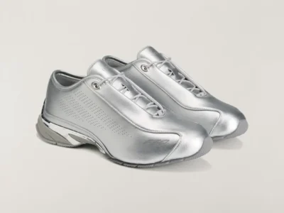 Pair of silver metallic low-top shoe with gray laces and perforated side panels on a light background