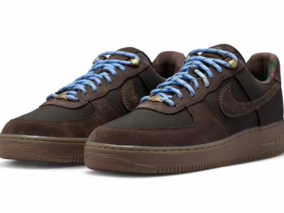 Pair of dark brown Nike Air Force 1 sneakers with bright blue laces on a white background