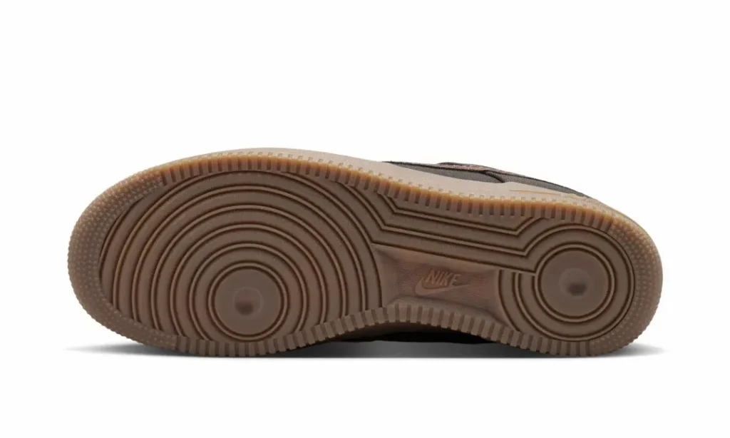Close-up of a sneaker’s brown rubber outsole with concentric circular tread and embossed Nike logo on a white background