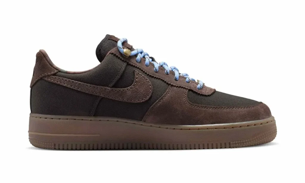 Brown low-top sneaker with suede overlays, black textile panels, blue laces and a matching brown rubber sole on white