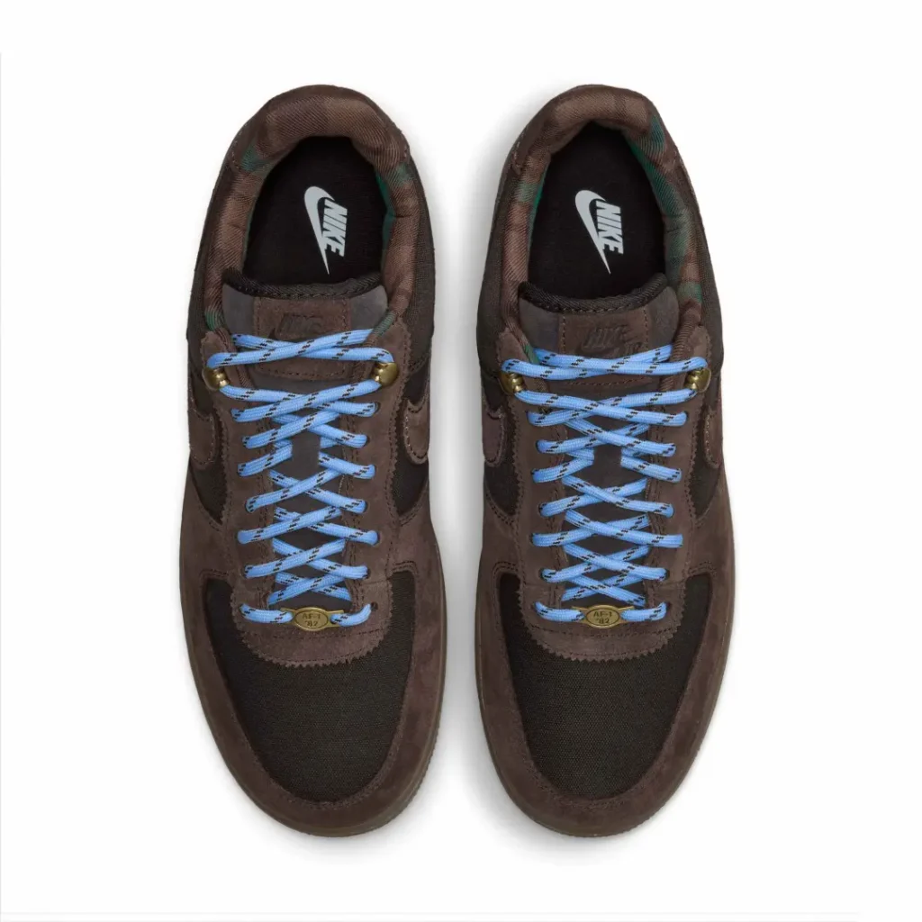 Pair of brown Nike sneakers with black mesh panels and bright blue laces, viewed from above on a white background
