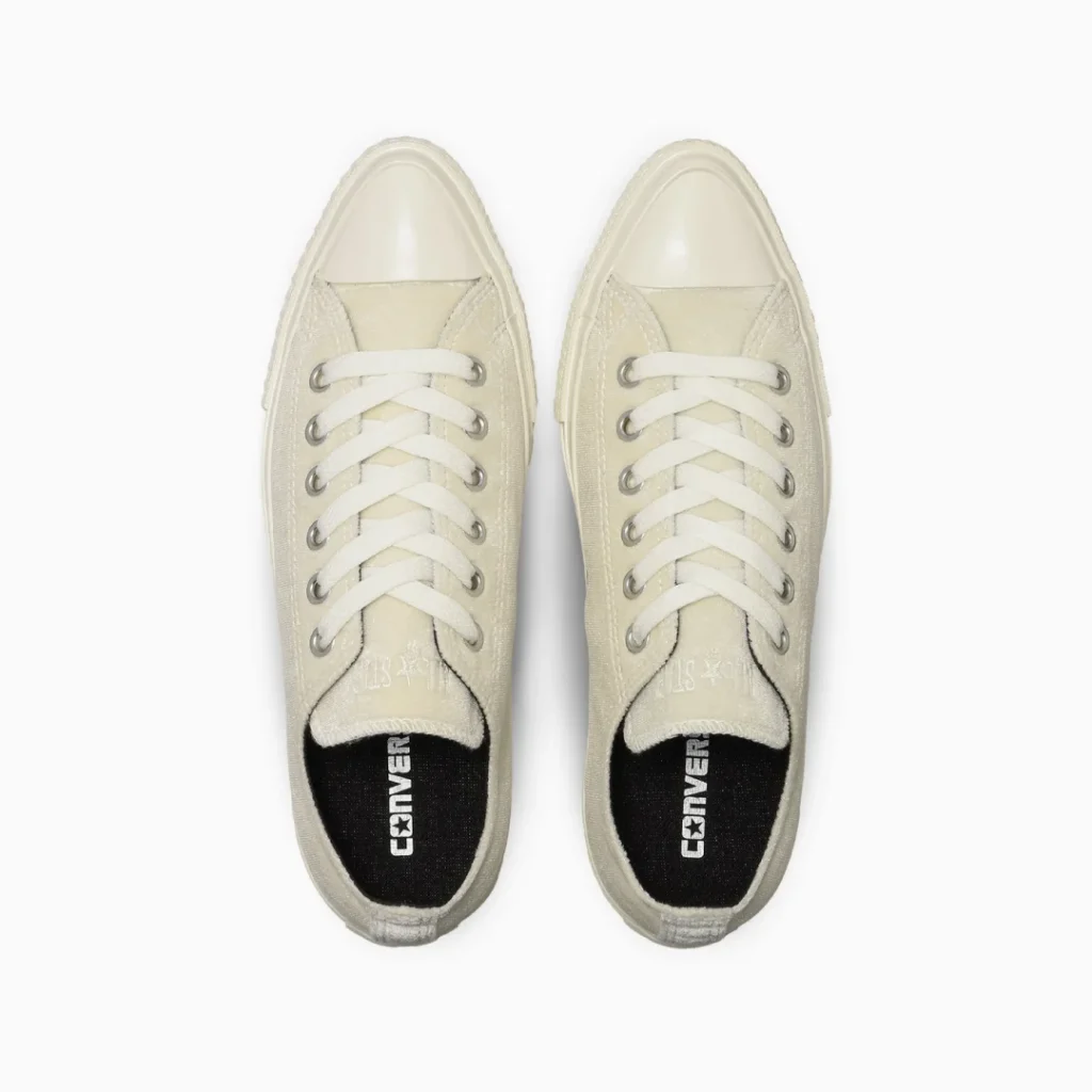 Pair of cream canvas lace-up sneakers with rubber toe caps and black Converse-branded insoles on a white background