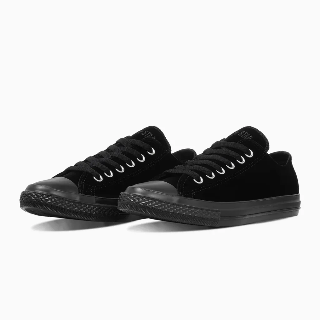 Pair of black low-top shoe with black laces, silver eyelets, textured rubber toe caps and soles on a white background