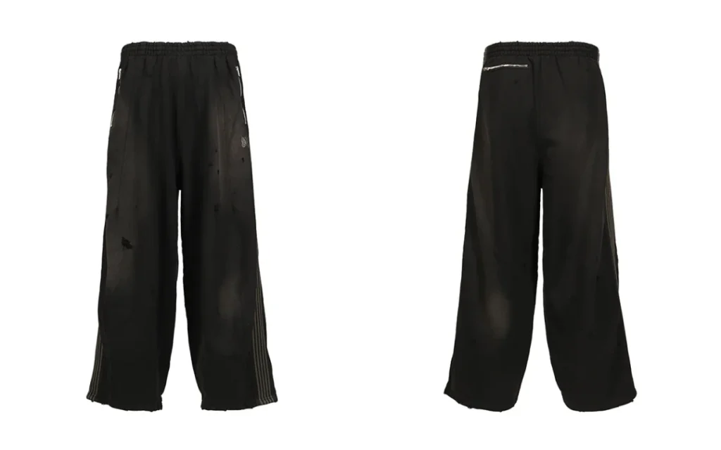 Front and back views of black wide-leg track pants with distressed details, side stripes, elastic waistband, and zip pockets