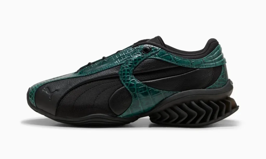 Black sneaker with dark green crocodile-textured overlays and a thick zigzag-patterned sole, shown in side profile on white