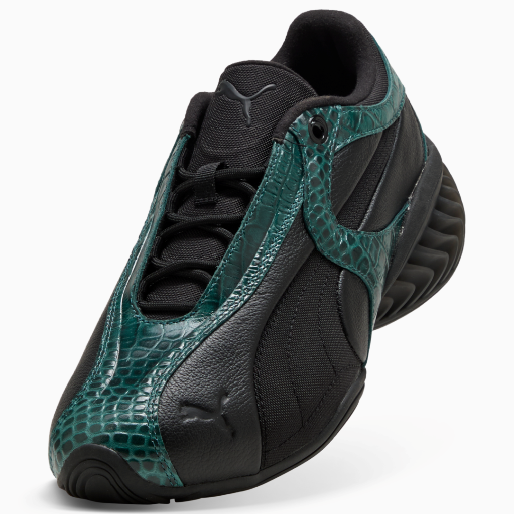 Black Puma sneaker with glossy teal snakeskin-patterned overlays and a ribbed sole, angled against a white background