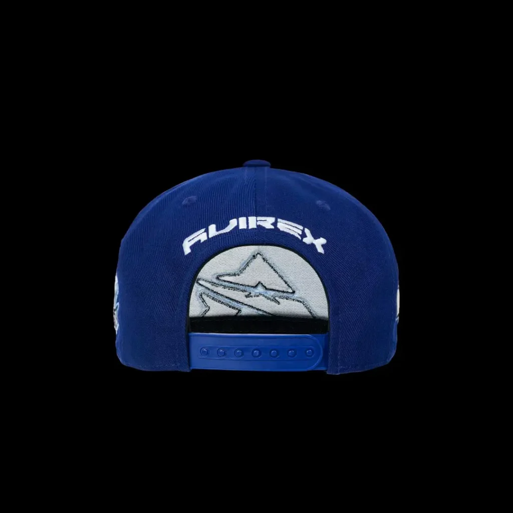 Blue snapback cap with white embroidered logo and mountain patch, shown from the back against a black background