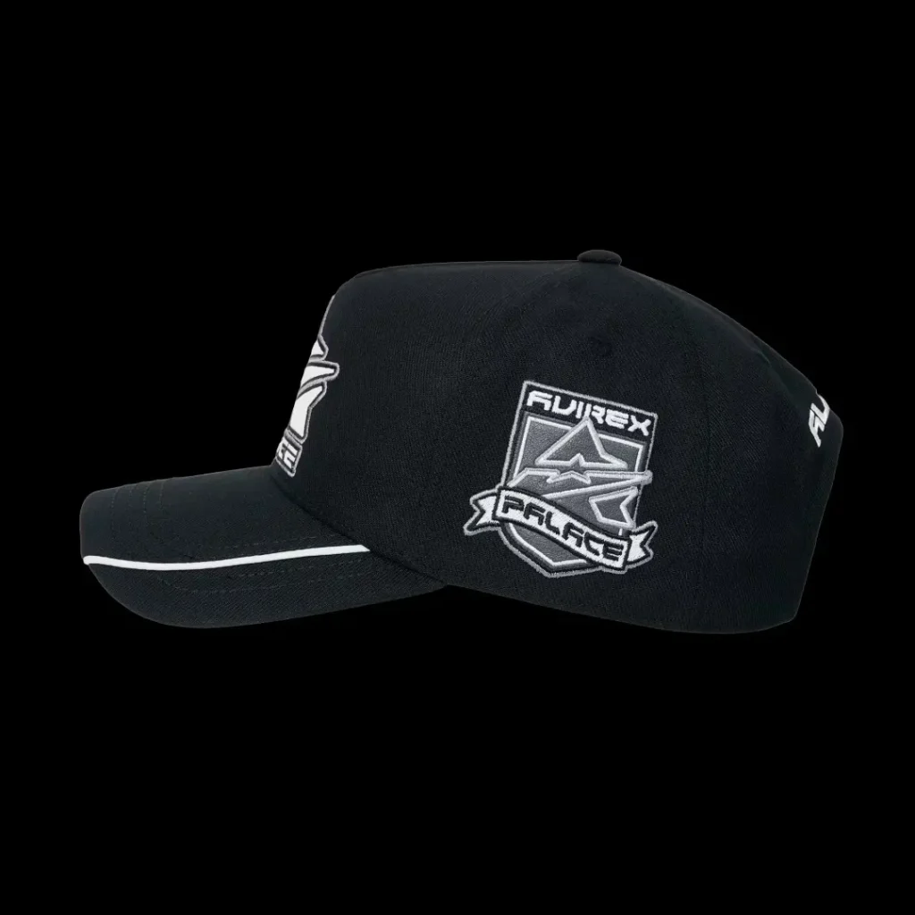 Black Fujirex Palace baseball cap with white embroidered logos and piping on the brim, isolated against a black background