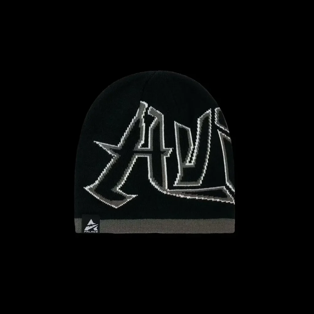 Black knit beanie with large white graphic lettering, gray ribbed band and small logo, isolated on black background