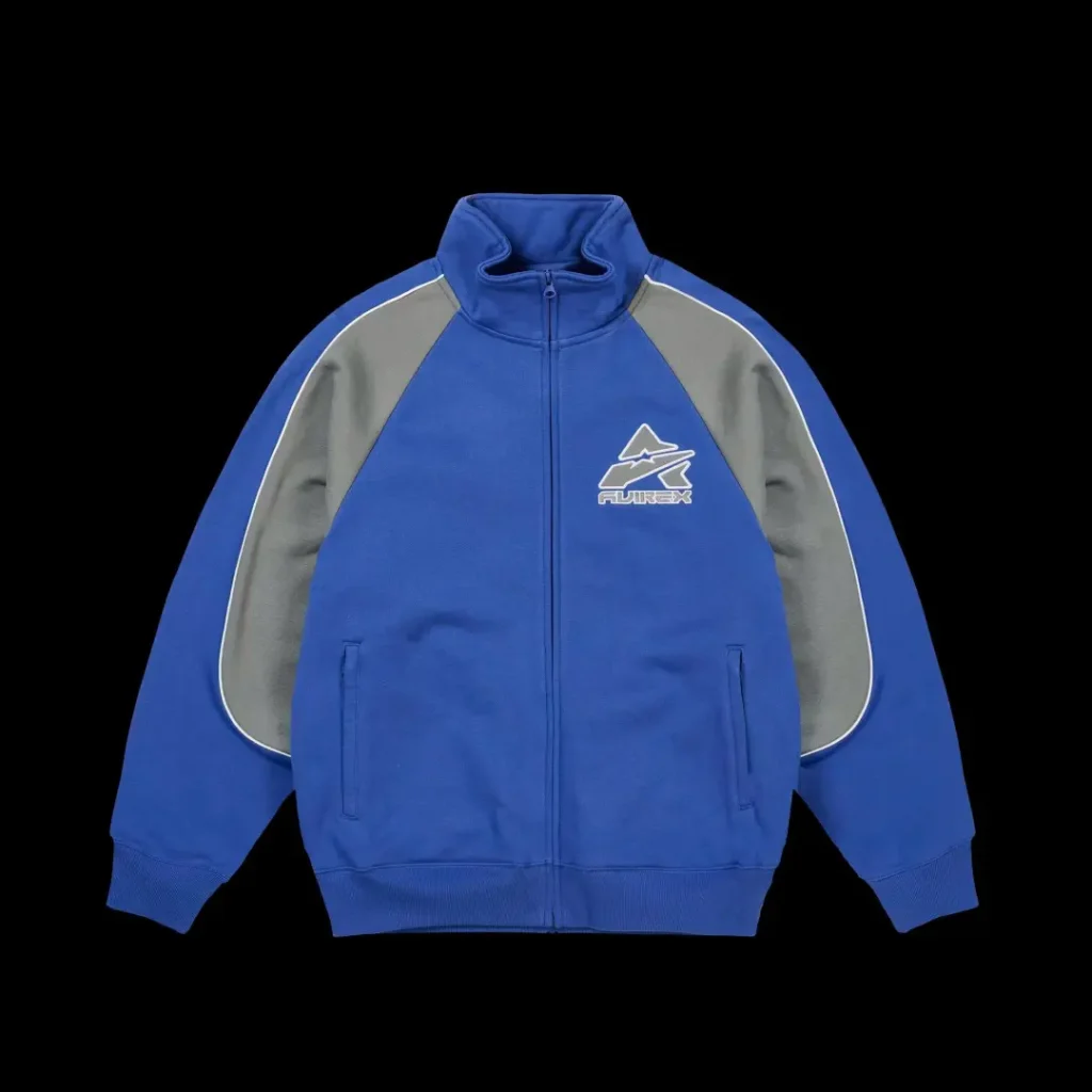 Blue zip-up jacket with gray sleeves, white piping, ribbed cuffs and hem, and a chest logo, shown against black background
