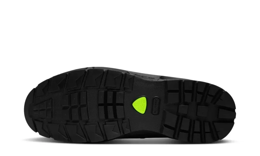 Black shoe outsole with deep tread blocks, a bright green triangular insert, and raised “ELECTRIC” lettering on white