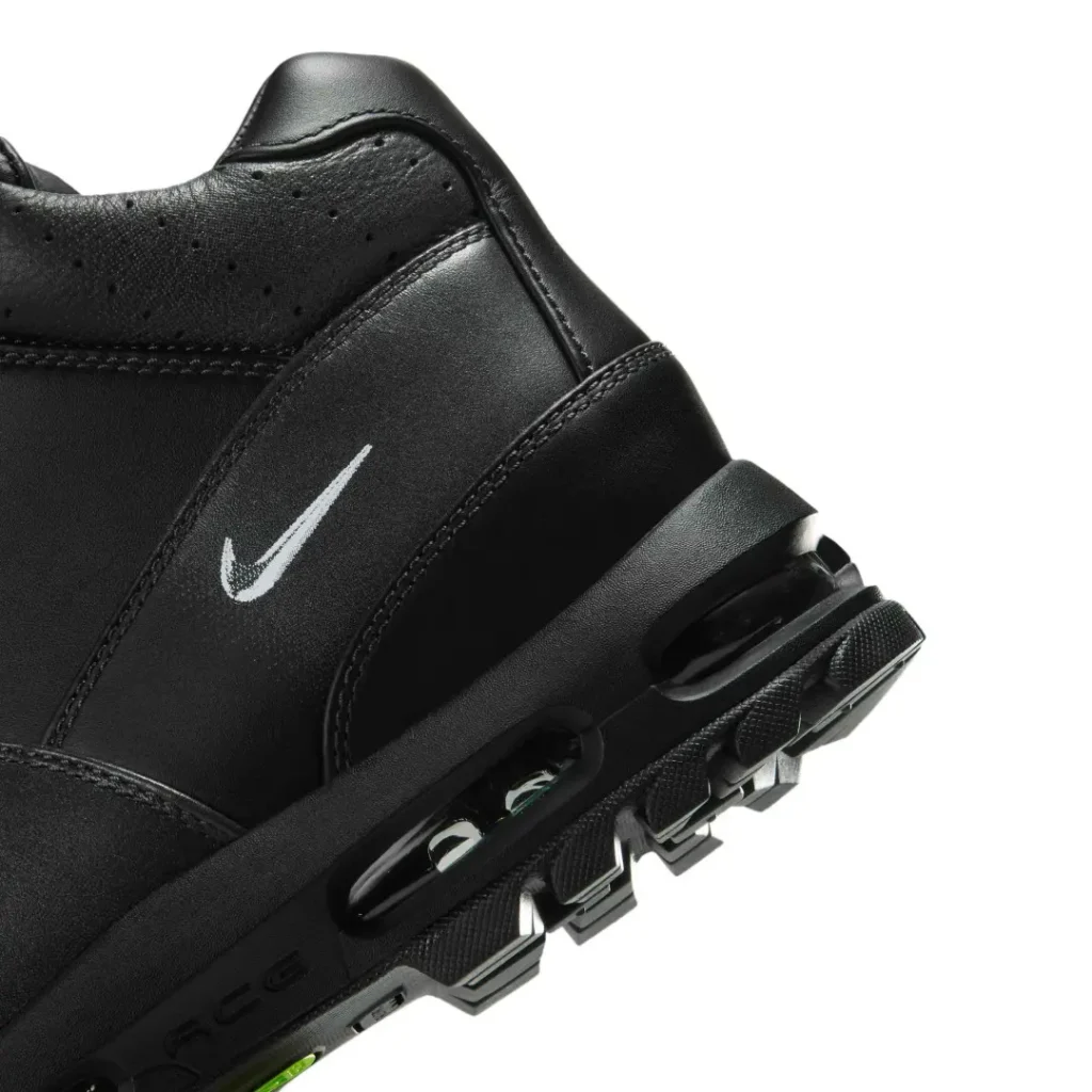 Close-up of a black Nike sneaker with a white swoosh, perforated upper, and rugged segmented sole on a white background