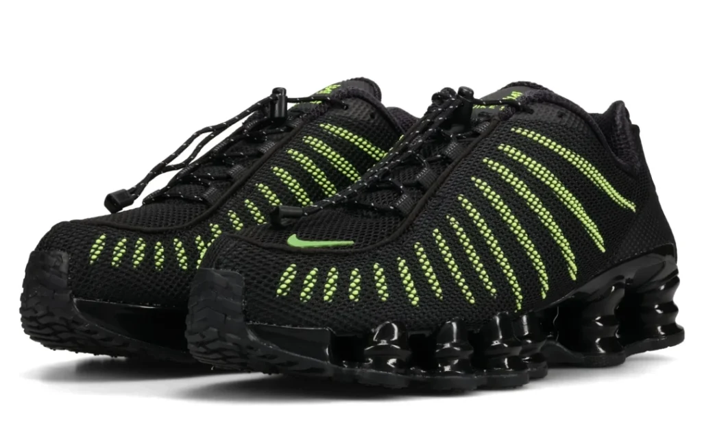Pair of black Nike sneakers with neon green striped detailing and segmented soles on a white background