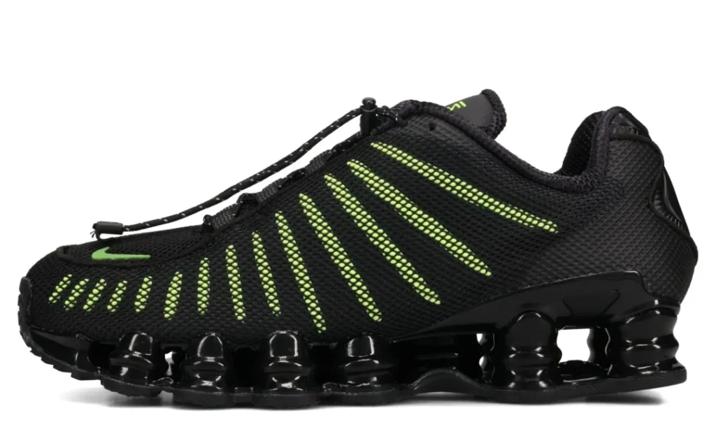 Black athletic sneaker with neon green dotted stripes and segmented black sole, shown in side profile against a white
