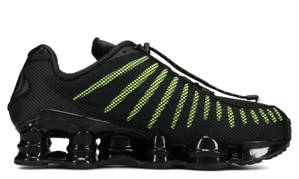 Black knit shoe with neon green side stripes and a glossy segmented sole, shown in profile on white background