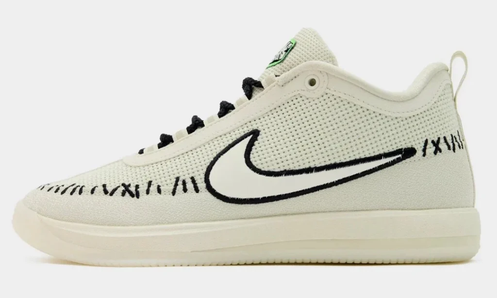 Cream Nike low-top sneaker with black laces, swoosh, and handwritten-style markings on a white background