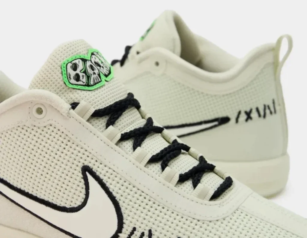 Close-up of cream Nike sneakers with black laces, swooshes, and a green tongue patch against a white background