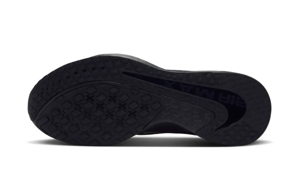 Black athletic shoe shown from the underside, highlight its texture rubber outsole and pattern tread on a white