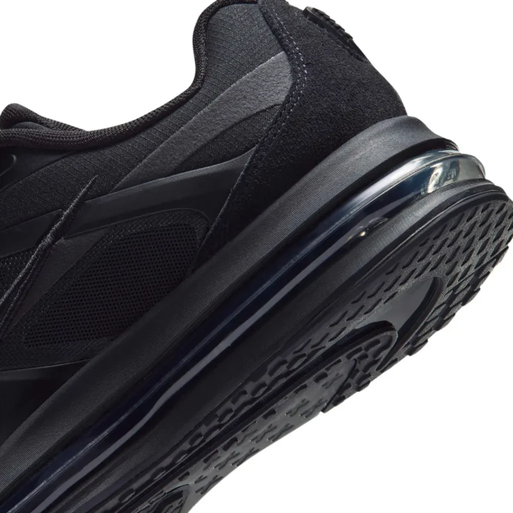Close-up of a black athletic shoe show layered mesh panels, textured upper, air cushioning, and patterned rubber sole on