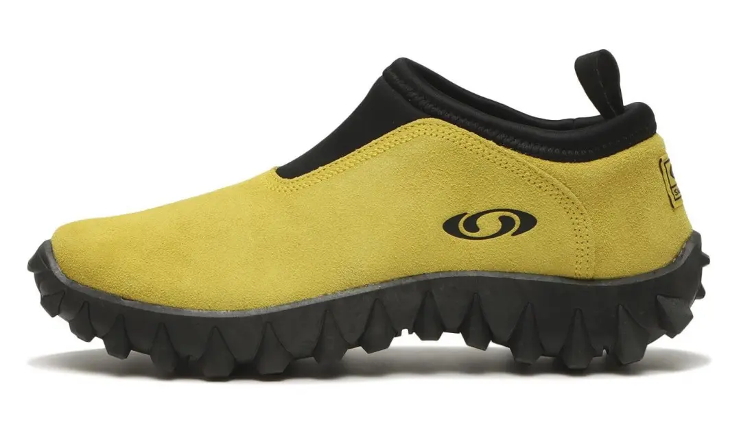 Yellow Salomon slip-on shoe with a black padded collar and rugged, lugged sole on a white background