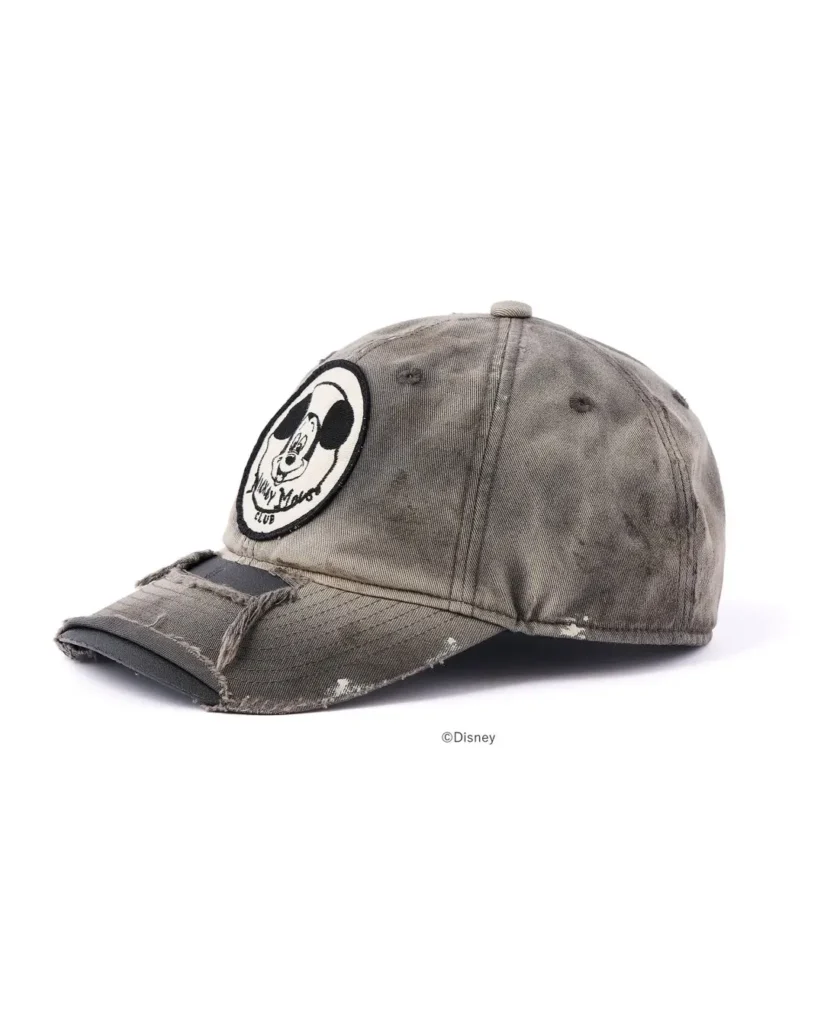 Distressed gray baseball cap with a frayed brim and circular Mickey Mouse patch on a white background