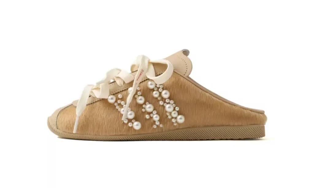 Tan sneaker with white laces and clustered pearl embellishments on the side, shown in profile against a white background